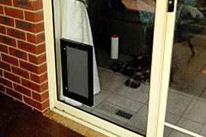 black coloured dog door installed into a glass sliding door
